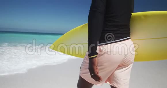 后景老人带着冲浪板在海滩散步视频的预览图