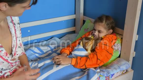 妈妈在床上给一个生病的女孩盖上毯子视频的预览图