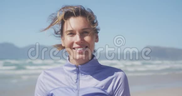 运动的女人微笑着看着海滩上的摄像机视频的预览图
