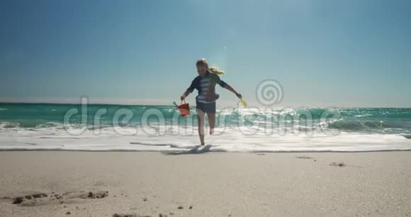 前景女孩带着玩具在海滩上奔跑视频的预览图