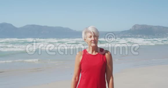 老妇人微笑着看着海滩上的摄像机视频的预览图