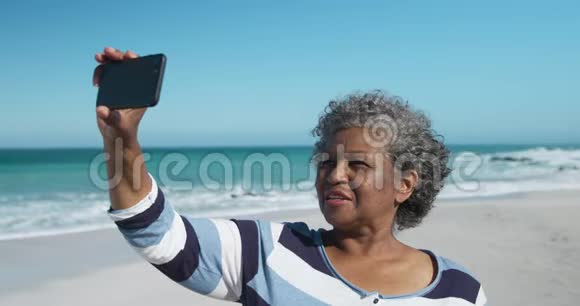 侧景老女人在海滩拍照视频的预览图