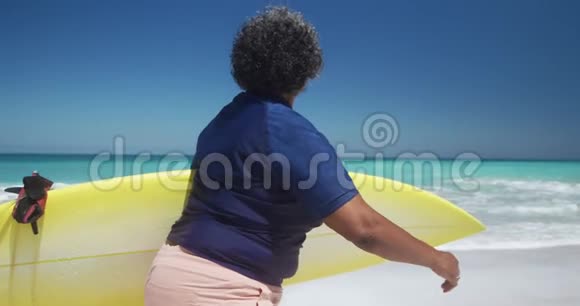 侧景老女人带着冲浪板走路视频的预览图