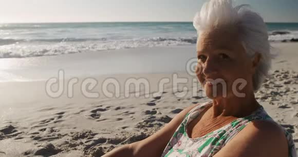侧景老妇人坐在一旁看着海滩视频的预览图