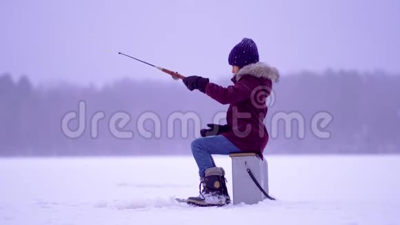 冬天在湖边钓鱼的女孩侧视视频的预览图