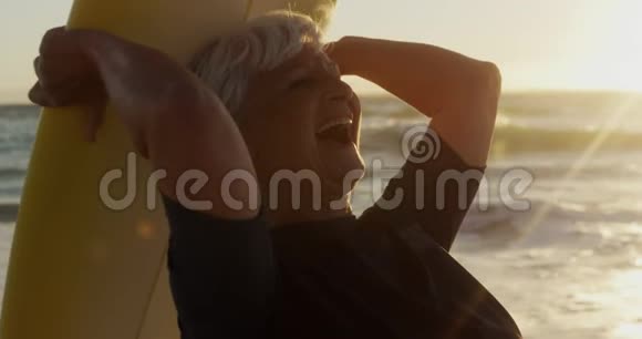 一边看一边带着冲浪板微笑的老女人视频的预览图