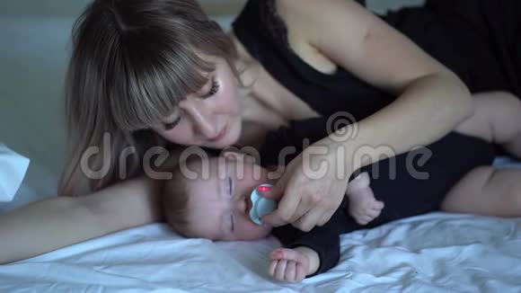 妈妈从熟睡的婴儿嘴里拿出一个奶嘴视频的预览图