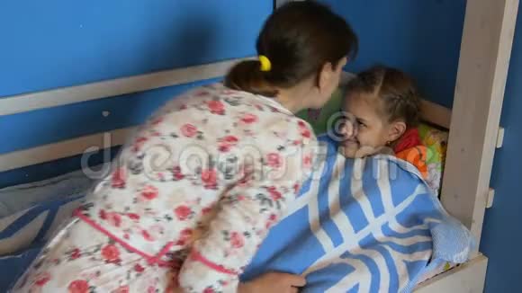 妈妈吻了一个生病孩子的额头额头躺在床上上面盖着一条毯子视频的预览图