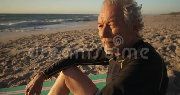从侧面看坐在沙滩上的老人视频的预览图