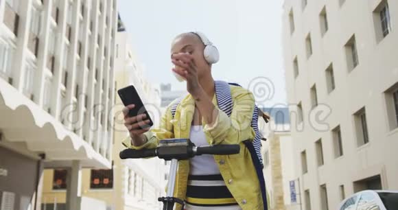 混合种族的女人在她的电动车上在街上听音乐视频的预览图