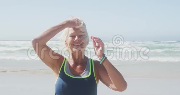 老妇人微笑着看着海滩上的摄像机视频的预览图
