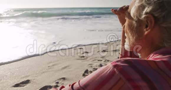 后景老人坐在远处看海滩视频的预览图