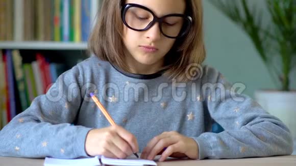 一个戴着大黑眼镜的女孩在笔记本上写字黄笔在右手关闭视野视频的预览图