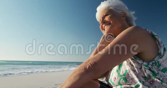 侧景老妇人坐在一旁看着海滩视频的预览图