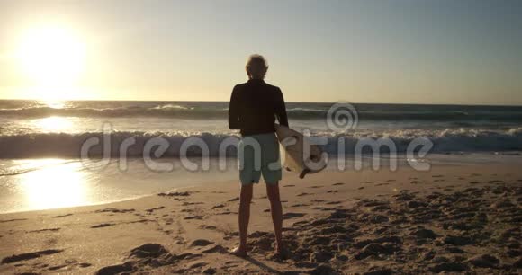 海滩冲浪板的后景老人视频的预览图