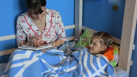妈妈坐在床上给生病的孩子读一本书视频的预览图