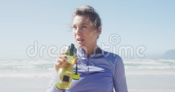运动妇女在海滩上饮水视频的预览图
