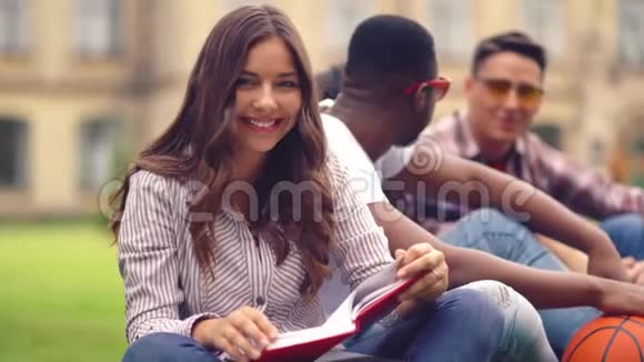 年轻的大一学生女孩在户外玩时看书视频的预览图