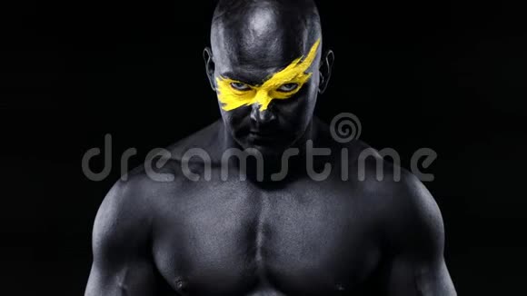男性健美运动员脸上有黄色的艺术和黑色的身体油漆胸部有肌肉彩色肖像视频的预览图