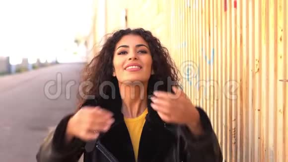 年轻的阿拉伯女人走在户外移动她的黑色卷发视频的预览图