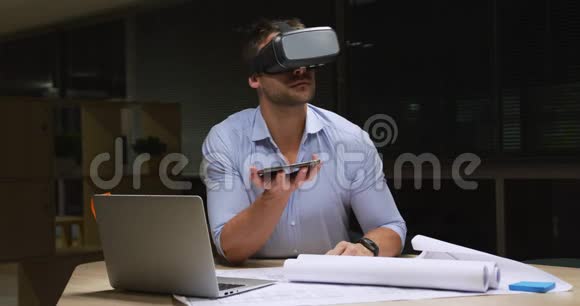 商人在笔记本电脑上工作在现代办公室里使用VR头盔视频的预览图