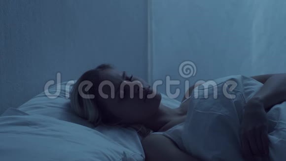 年轻女子晚上躺在床上患有失眠症美丽的金发女郎暮光之城视频的预览图
