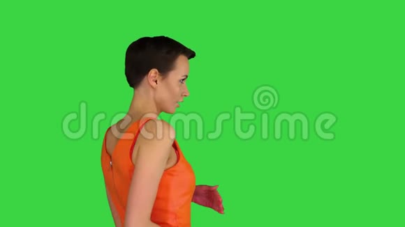 美丽的女人穿着华丽的橙色连衣裙在绿色屏幕上跳舞Chroma键视频的预览图