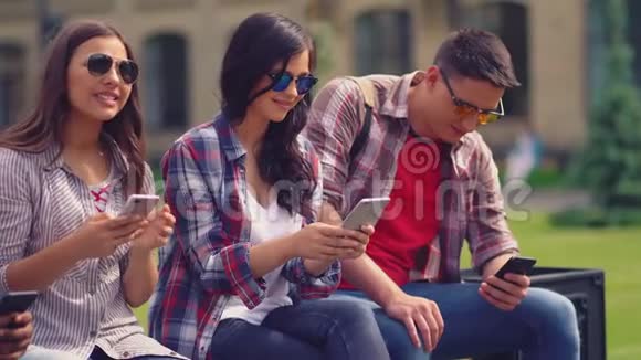 年轻人坐在户外的智能手机里视频的预览图