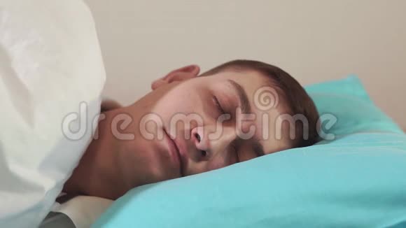 在柔软的枕头上睡着了的年轻人特写有选择的专注舒适的床健康的睡眠视频的预览图