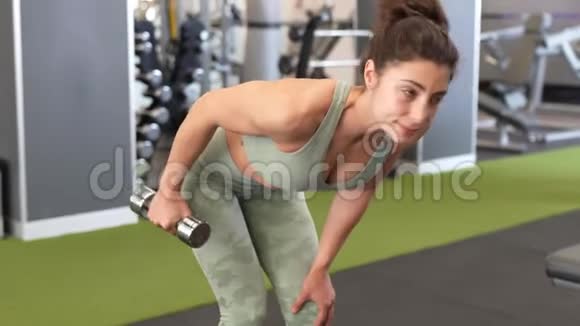 在健身房里用哑铃做肱三头肌和肱二头肌的女人视频的预览图