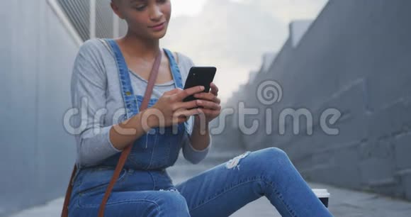 混合种族妇女使用智能手机坐在户外楼梯视频的预览图