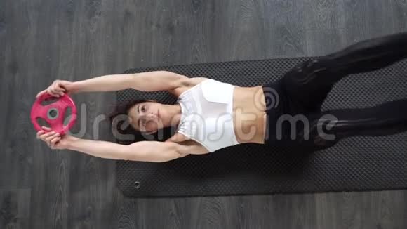 在瑜伽垫上做仰卧起坐的年轻女运动员视频的预览图