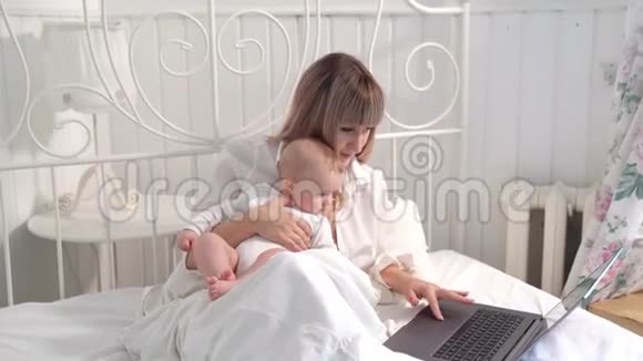 妈妈带着婴儿在床上用电脑工作视频的预览图