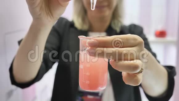女化验员在试液中倒入化妆品油进行身体护理生产视频的预览图