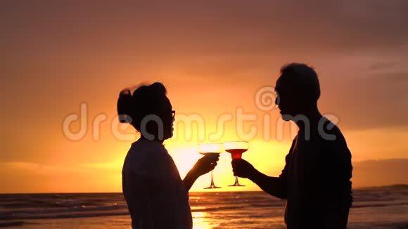 Silhouette亚洲夫妇年长的老人退休后可以在海滩上放松喝葡萄酒视频的预览图