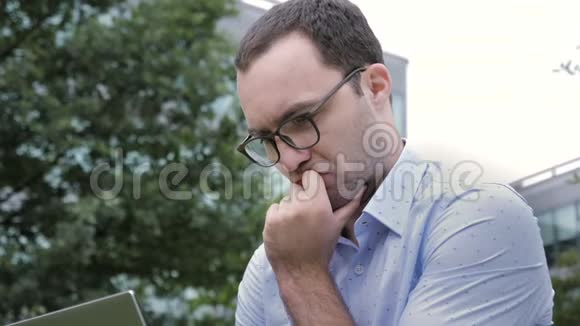 英俊的年轻商人用笔记本电脑坐着思考和思考视频的预览图
