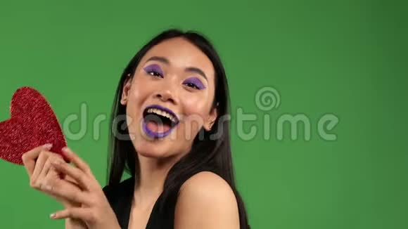 一个亚洲微笑的女人手里拿着一张红纸跳舞脸上挂着一张孤立的绿纸视频的预览图
