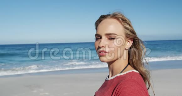 站在沙滩上看镜头的女人视频的预览图