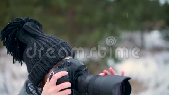 一个女孩在冬天的森林里用照相机拍照视频的预览图