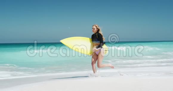 在沙滩上奔跑的女人手臂下拿着冲浪板视频的预览图