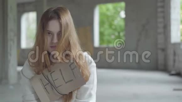 一幅悲伤的女孩的肖像留着长长的红色头发在废弃的大楼里的一个尘土飞扬的空房间里感觉不好一个迹象表明视频的预览图