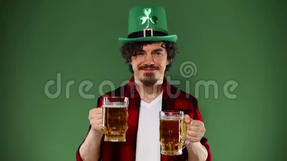 圣帕特里克节年轻的啤酒节男子提供大啤酒杯与饮料隔离在绿色背景动作缓慢视频的预览图