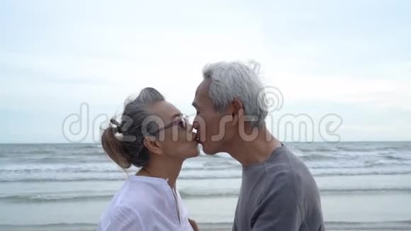 亚洲夫妇年长长者退休后休息放松亲吻和拥抱日落海滩视频的预览图