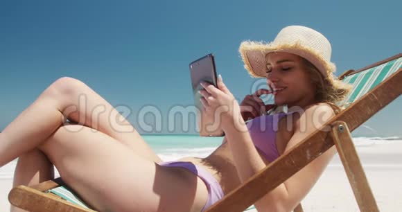 在海滩上使用数码平板电脑的女人视频的预览图