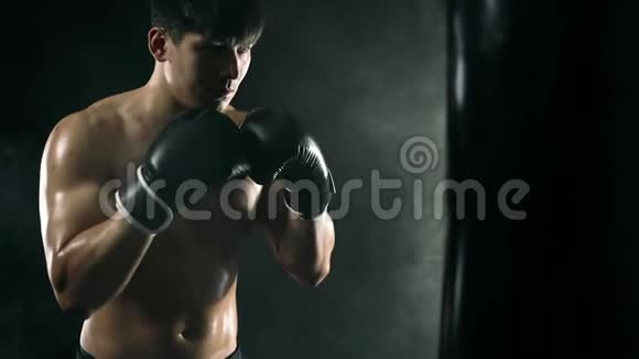 拳击概念一个戴手套的拳击手背着黑色的拳击袋个人体育娱乐慢视频的预览图