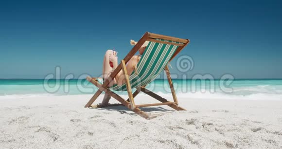 在沙滩躺椅上喝鸡尾酒的女人视频的预览图