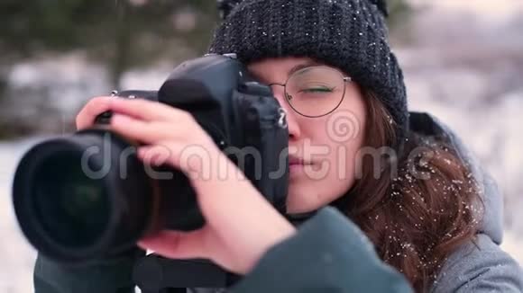 在下雪的一天一位女摄影师为冬天的森林拍照视频的预览图