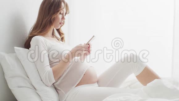 快乐孕妇使用智能手机设备怀孕母性和期望概念视频的预览图