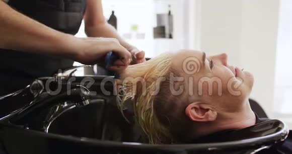 侧视妇女的头发被理发师梳过视频的预览图