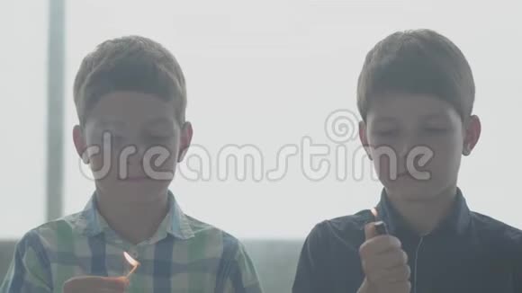 两个小双胞胎兄弟在窗户前的烟雾弥漫的房间里玩火孩子们拿出火柴视频的预览图